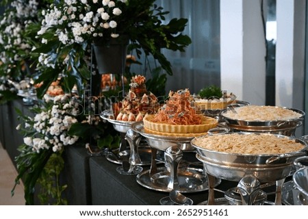 elegant buffet table setup for special events, gourmet catering display with floral decoration, large self-service food station in banquet hall

