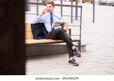 Elegant businessman drinking hot coffee waiting for train