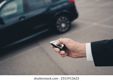 Elegant businessman in parking lot unlocking his car with remote key, reflecting modern travel and business lifestyle - Powered by Shutterstock