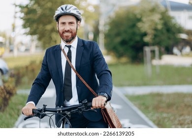 Elegant businessman in protective helmet looking at camera, smiling, while cycling to work outdoors. Portrait of happy executive using eco transport, while commuting to job. Concept of eco lifestyle. - Powered by Shutterstock