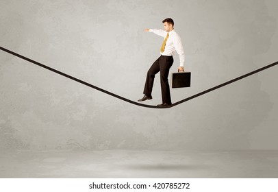An Elegant Businessman In Suit Balancing On A Tight Rope With A Briefcase In Front Of Grey Urban Wall Background Environment Concept