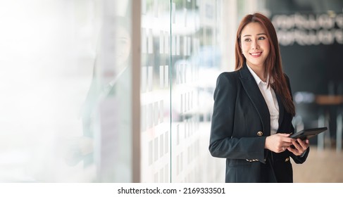 Elegant businesswoman standing in office with digital tablet. - Powered by Shutterstock