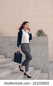 Elegant businesswoman talking on the phone while walking outdoors