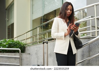 Elegant businesswoman walking down street and checking notifications on smartphone - Powered by Shutterstock