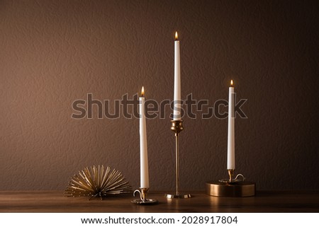 Elegant candlesticks with burning candles on wooden table