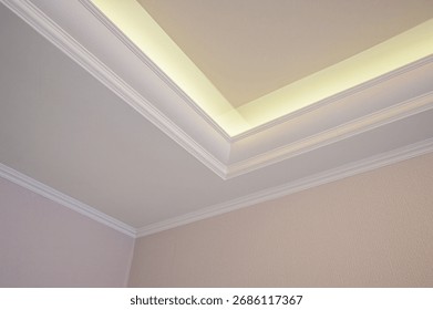 Elegant ceiling corner featuring white crown molding and indirect lighting.  Clean lines soft glow