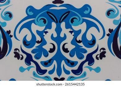 Elegant ceramic tile pattern featuring ornate, symmetrical damask-style motifs in varying shades of blue and black on a white background.