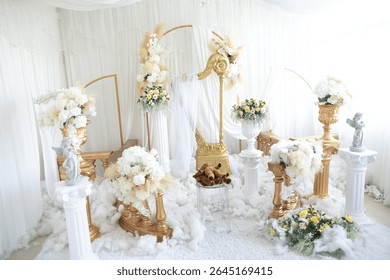 An elegant ceremonial setup with a golden chair, white drapes, floral arrangements, and white cloud like decorate, likely for a wedding or special event.