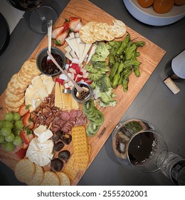 An elegant cheese and fruit board featuring assorted cheeses, fresh fruits, charcuterie, bread, and crackers, paired with glasses of red wine, perfect for a sophisticated gathering. - Powered by Shutterstock