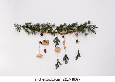 Elegant Christmas decoration hanging on white wall. Christmas decoration - fir branch with garland, gift boxes and cones. New Year decoration. - Powered by Shutterstock