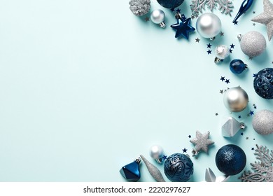 Elegant Christmas decorations on light blue background top view. Flat lay dark blue and silver baubles, snowflakes, stars, confetti. Xmas banner mockup, postcard template