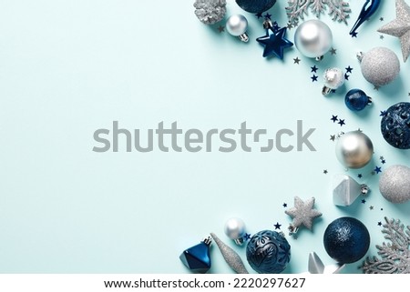 Elegant Christmas decorations on light blue background top view. Flat lay dark blue and silver baubles, snowflakes, stars, confetti. Xmas banner mockup, postcard template