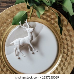 Elegant Christmas place settings with natural branches decoration and golden plate. Reindeer figurine on the dish on wood table background - Shutterstock ID 1837255069