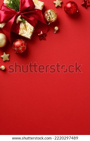 Elegant Christmas vertical banner design. Flat lay Christmas gift box, ornaments, baubles on red background.