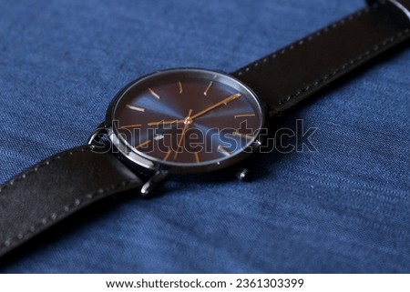 Elegant Close Up Navy And Black Wrist Watch On Blue Fabric Background