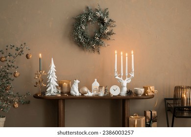 Elegant composition of christmas living room interior with wooden console, stylish wreath, deer candlestick with candle, clock, christmas tree, gifts and personal accessories. Home decor. Template.	
