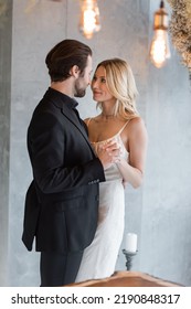 Elegant Couple Holding Hands Under Light Bulbs In Restaurant