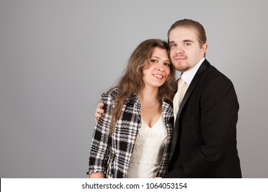 Elegant couple smiling for the camera while embracing. On grey background.