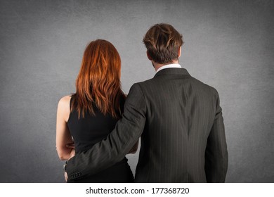 Elegant Couple Studio Portrait From Behind Against Grunge Background.