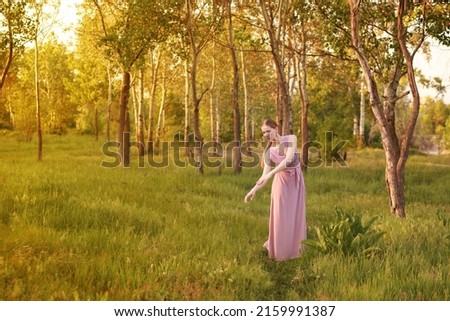 an elegant dancing woman in nature in a grove at sunset in the summer. postcard. Banner