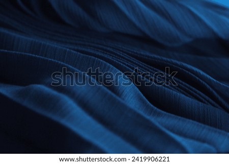 Elegant dark blue silk fabric. Aesthetic aquamarine tissue texture, folded dress textile background. Ocean dunes, luxurious pleated chiffon clothing, indigo 3d abstract sea waves