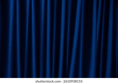 Elegant dark blue velvet curtain with soft folds and light reflection. Luxurious fabric texture background for stage, theater, or interior design.