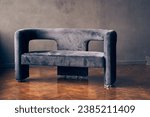 An elegant dark-colored sofa on a dark wall. One object on a dark background with space to copy. High quality photo