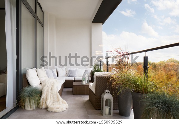 Elegant decorated balcony with rattan outdoor\
furniture, bright pillows and\
plants