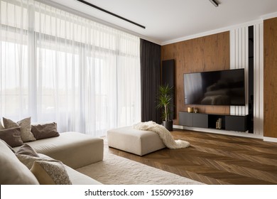 Elegant Designed Living Room With Window Wall, Big Television Screen And Wooden Elements