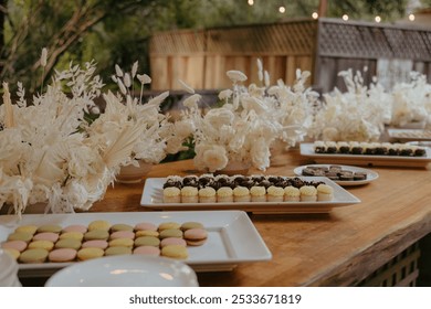 An elegant dessert table with assorted pastries and white floral arrangements in an outdoor setting - Powered by Shutterstock