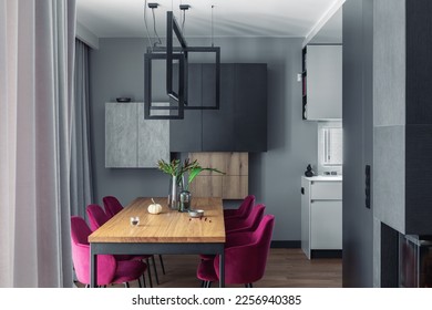 Elegant dining room interior design with velvet chairs, design wooden table, lamps and beautiful personal accessories. Open space. Concrete walls. Modern home decor. Template.