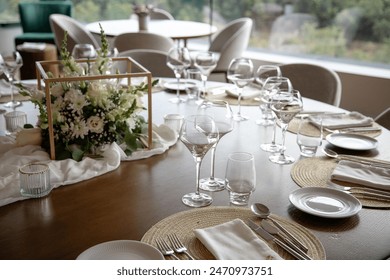 Elegant dining table set for a special event, featuring a beautiful floral centerpiece, wine glasses, and finely arranged utensils, creating a sophisticated and welcoming atmosphere.