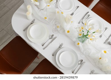 Elegant dining table setting with white tablecloth, calla lilies, and candles for a special occasion