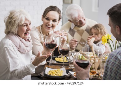 Elegant dinner of a multigenerational family, with a grandmother raising her glass in a toast - Powered by Shutterstock