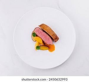 Elegant dish of sliced duck breast with fresh peach pieces, styled delicately on a round, white porcelain plate - Powered by Shutterstock