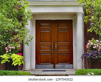 Elegant Double Wooden Front Door And Portico Entrance Surrounded By Flowers Of Upper Class House