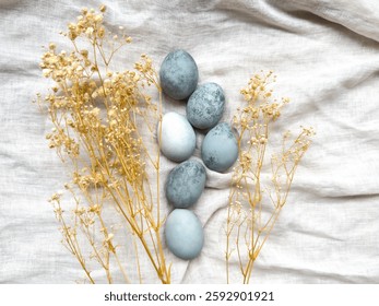 elegant easter composition with painted eggs, dried flowers on light linen background. easter background. easter still life. spring background.