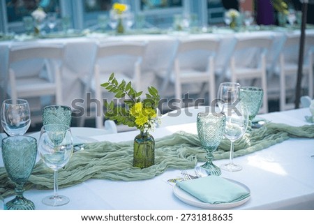 Elegant event dining table setup with sage green decor, vintage embossed glassware, and floral runner detail. Perfect for weddings and upscale celebrations.