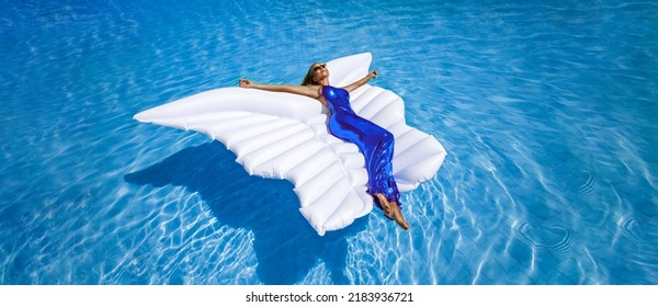 Elegant Fashion Model In Long Gown Dress Is Lying On A Mattress In The Pool . Elegance. Classy Woman In Amazing Dress Is Posing In The Pool On Maldives Island. Couture. Vogue. Siren.
