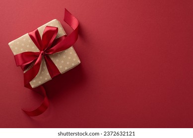 Elegant felicitations. Top view of gift box wrapped in craft paper and a red ribbon, set on a marsala background. Add your message or advert - Powered by Shutterstock