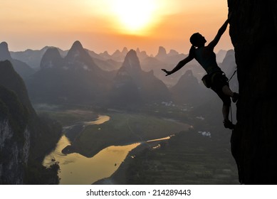 Elegant female extreme climber silhouette against the sunset over the river. China, typical Chinese landscape with mountains and river. - Powered by Shutterstock