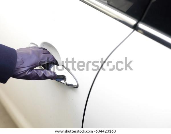 Elegant female hand wearing  leather glove\
opening a car door, cropped outdoor shot\
