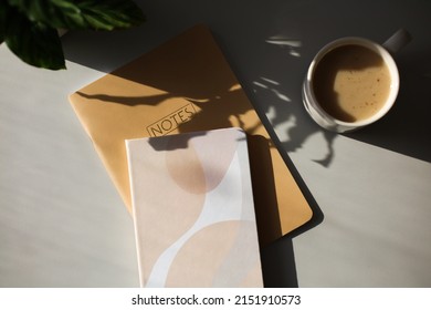 Elegant Feminine Workspace With Notebooks, Cup Of Coffee, Plant On Table In Sunshine. Flat Lay, Top View.