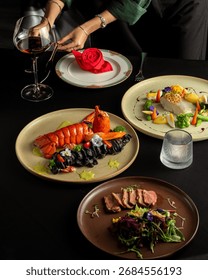 Elegant fine dining table setting with lobster, beef slices, gourmet seafood, vegetables, and red wine, beautifully plated for luxury restaurant experience