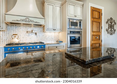 Elegant french country style kitchen with blue cast iron oven marbled countertops soft yellow wood cupboards gleaming hardwood floors  - Powered by Shutterstock