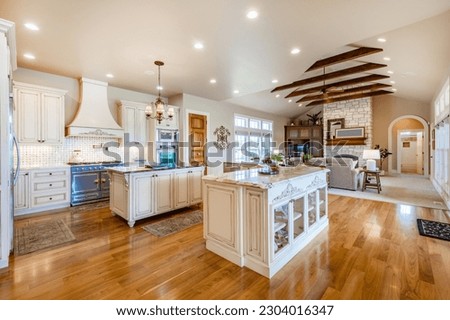 Elegant french country style kitchen with blue cast iron oven marbled countertops soft yellow wood cupboards gleaming hardwood floors 