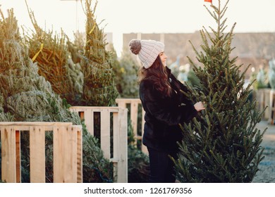 Elegant girl buys a Christmas tree. Woman in a fur coat. Beautiful lady with dark hair.