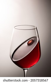 An elegant glass, half filled with red wine and with a funnel on the surface.