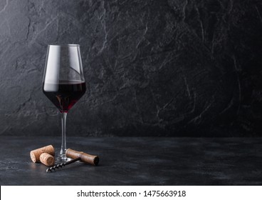 Elegant glass of red wine with corks and corkscrew on black stone background. - Powered by Shutterstock