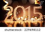 Elegant gold 2015 New Year background with textured golden numbers and twirled gold ribbon on a reflective dark brown surface for your seasonal greeting or invitation